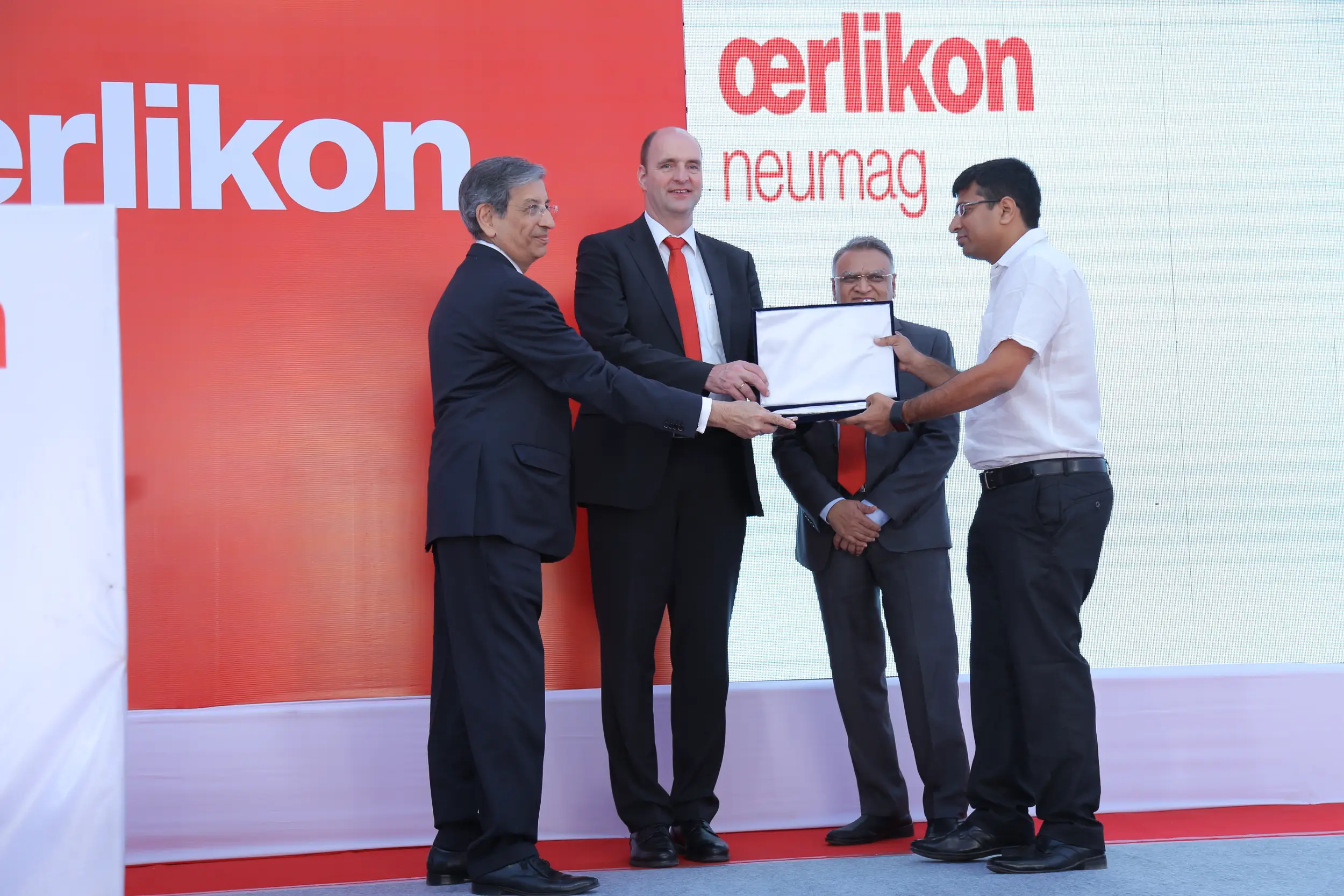 Men lighting ceremonial lamp at event with ITT banner in background